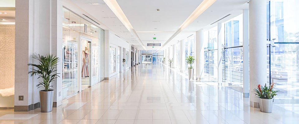 bright, modern shopping mall hallway with large windows and storefronts